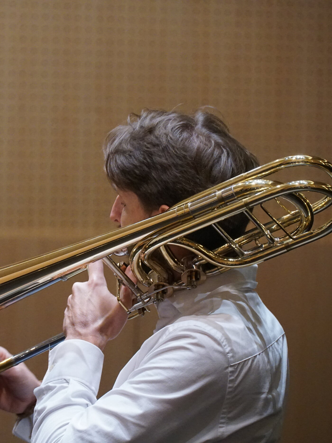 Trombonista tocando un trombón baixo, de perfil