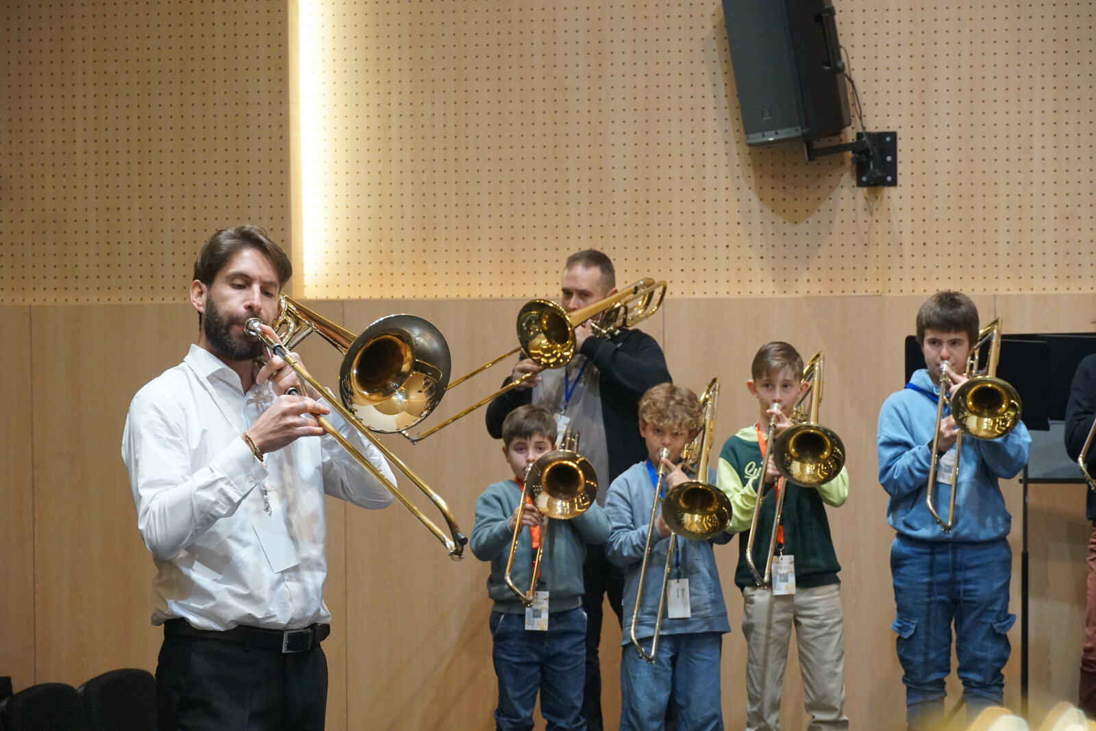 Un profesor tocando diante dunha fila de cativos cos seus trombóns