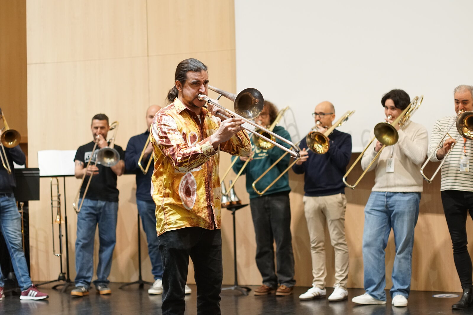 Un solista cunha camisa dourada tocando diante do grupo